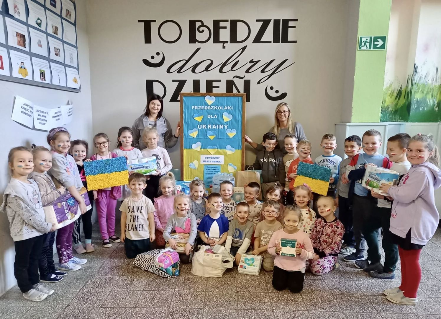 Grupa pięcio i sześciolatków z wychowawczyniami przy strefie zbiórki dla Ukraińców.