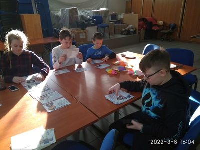 Dzieci z Placówki Wsparcia Dziennego czytają i słuchają informacji nt. sławnych kobiet.