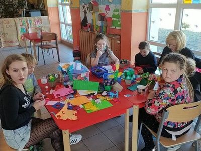 Dzieci z Placówki Wsparcia Dziennego z Lasek wykonują kwiaty z krepiny.