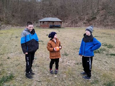 Trzej chłopcy z PWD w Sulechowie pozują do zdjęcia  na placu zabaw. W tle wiata ogniskowa i drzewa.