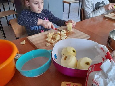 Dwie dziewczynki z PWD w Sulechowie krojące jabłka. Na stole widać jabłka, mąkę, margarynę, proszek do pieczenia.