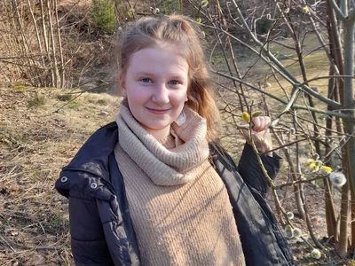 Dziewczynka z Placówki Wsparcia Dziennego w Sulechowie pozująca do zdjęcia przy wierzbie.