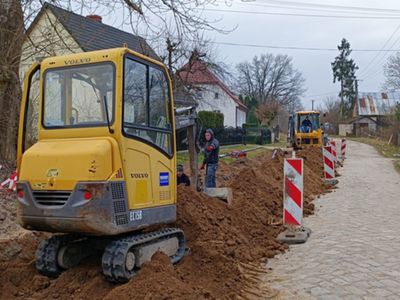 Wykopy pod wodociąg w Gorzycy, koparka i pracownicy w tle.