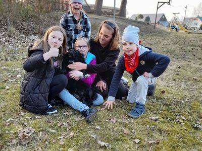 Cztery dziewczynki i chłopiec pozujący do zdjęcia z psem. W tle drzewa.