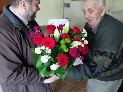 Wójt Radosław Nowakowski wręcza kwiaty seniorowi z Karwic - Stefanowi Fulko.
