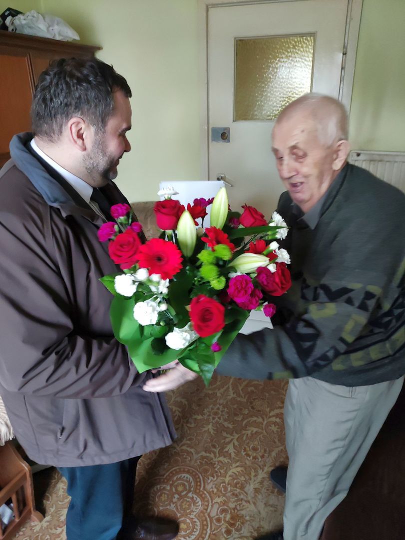 Wójt Radosław Nowakowski wręcza kwiaty seniorowi z Karwic - Stefanowi Fulko.