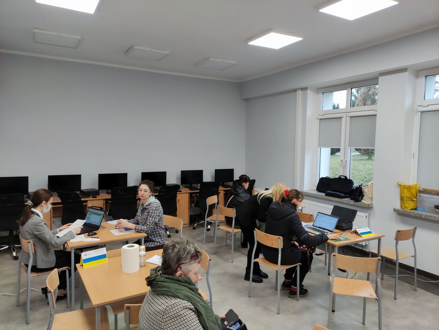 Obywatele Ukrainy podczas wypełniania dokumentów przy pomocy pracownic ZUS.