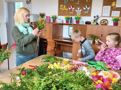 Troje dzieci i mama przygotowują palmy w domu wiejskim w Ostrowcu.