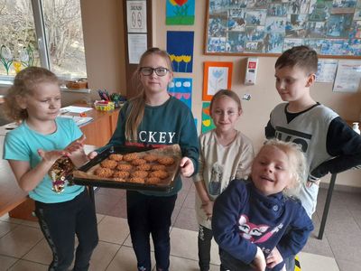 Cztery dziewczynki i chłopiec z Placówki Wsparcia Dziennego w Sulechowie pozujący do zdjęcia z przygotowanymi przez siebie ciasteczkami owsianymi.