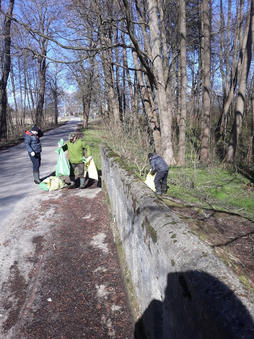 Trzech mężczyzn z workami pełnymi śmieci.