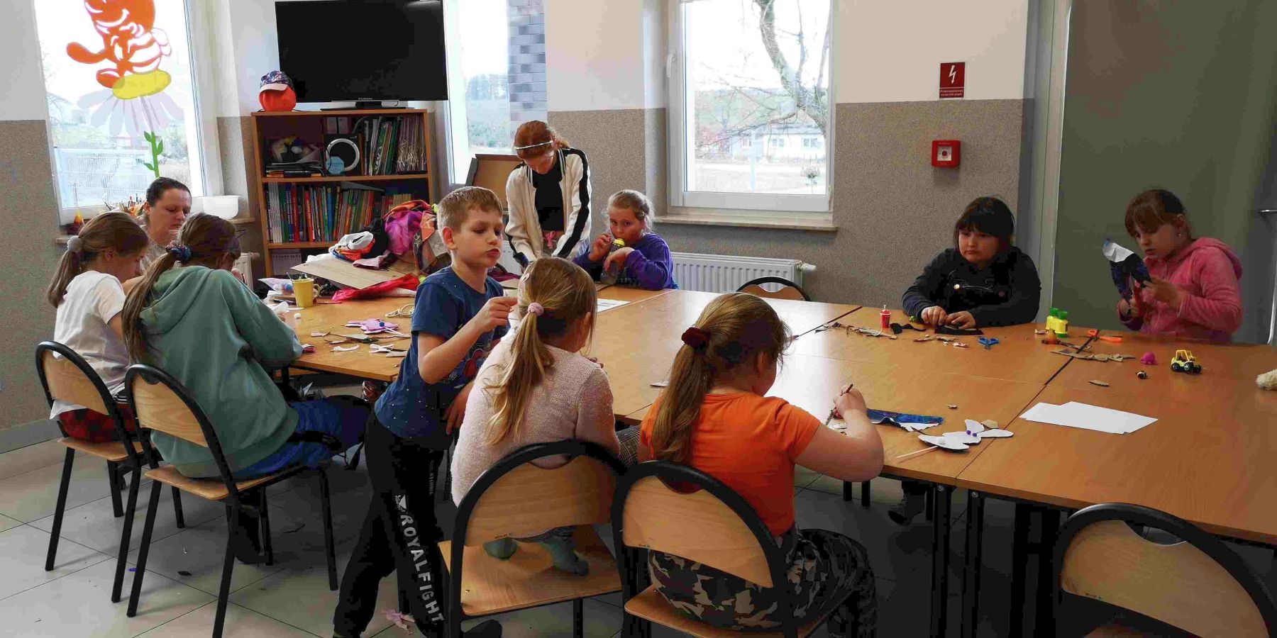 Dzieci z Placówki Wsparcia Dziennego w Kusicach z wychowawczynią podczas zajęć plastycznych.