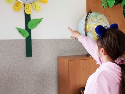 Dziewczynka z Placówki Wsparcia Dziennego w Kusicach wskazuje godzinę na zegarze ściennym. 