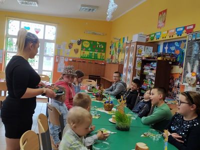 Wychowankowie z Placówki Wsparcia Dziennego w Laskach składają sobie życzenia przy stole Wielkanocnym.