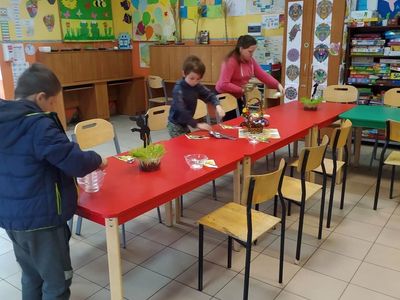 Wychowankowie z Placówki Wsparcia Dziennego w Laskach dekorują Wielkanocny stół.