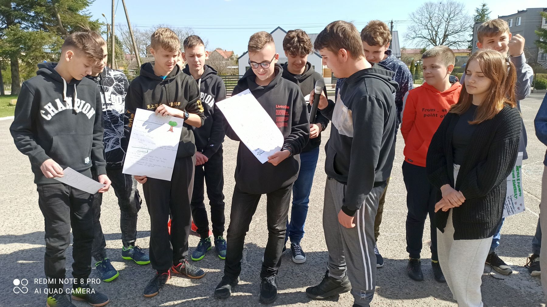 Grupa uczniów Zespołu Szkół w Ostrowcu podczas obchodów Dnia Ziemi na placu przed szkołą.