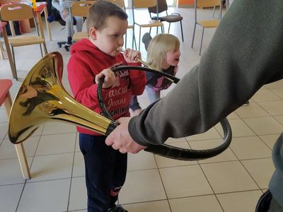 Słuchanie i próba gry na rogu dzieci z Placówki Wsparcia Dziennego w Laskach.
