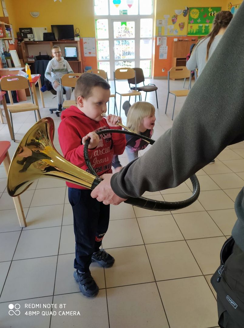Słuchanie i próba gry na rogu dzieci z Placówki Wsparcia Dziennego w Laskach.