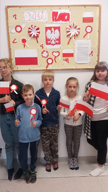 Wychowankowie Placówki Wsparcia Dziennego w Ostrowcu upamiętniający Dzień Flagi z flagami w dłoniach.