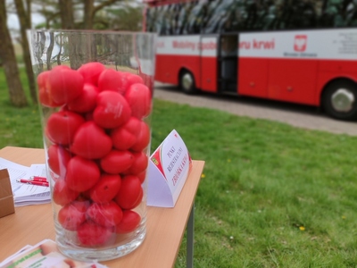 Zdjęcie piłeczek w kształcie serca z podziękowaniami na tle krwiobusa.