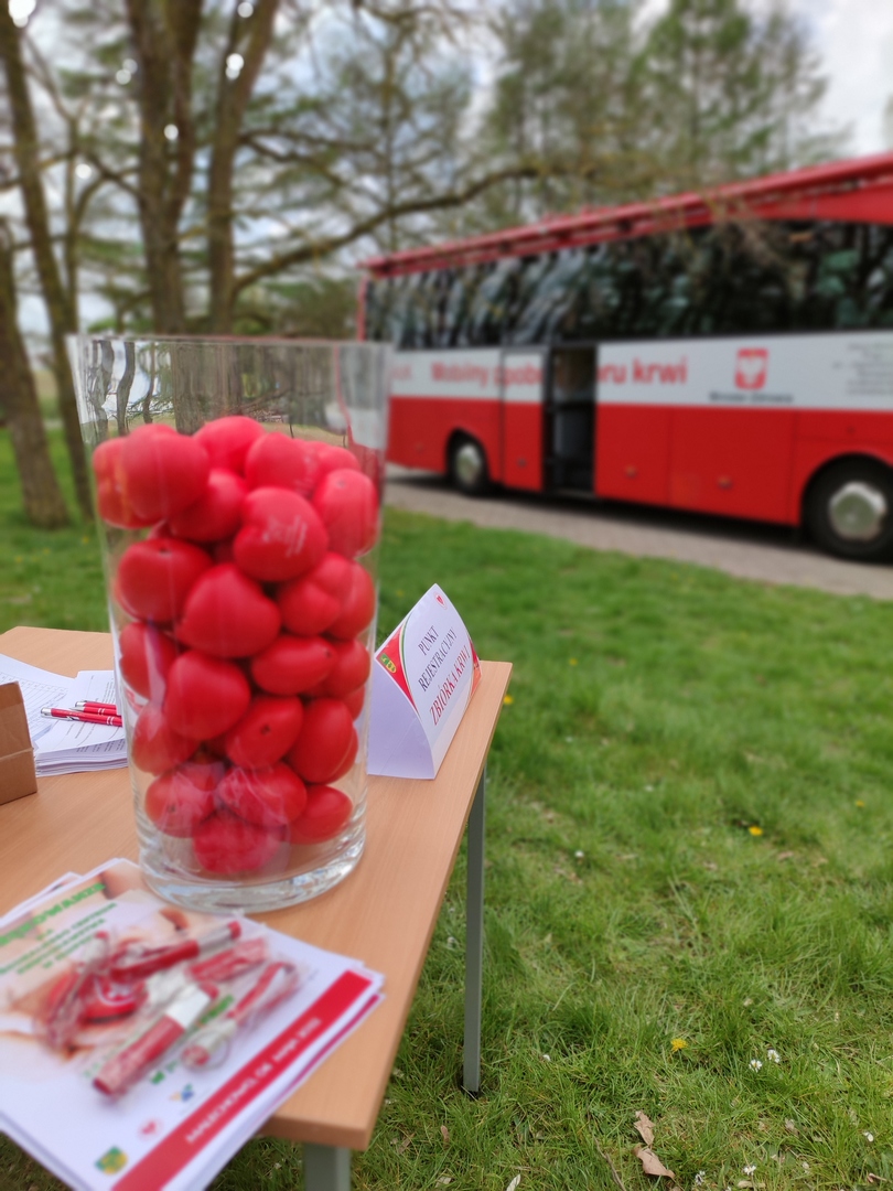 Zdjęcie piłeczek w kształcie serca z podziękowaniami na tle krwiobusa.