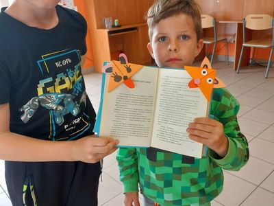 Podopieczni z Placówki Wsparcia Dziennego w Laskach prezentują wykonane przez siebie zakładki do książek.