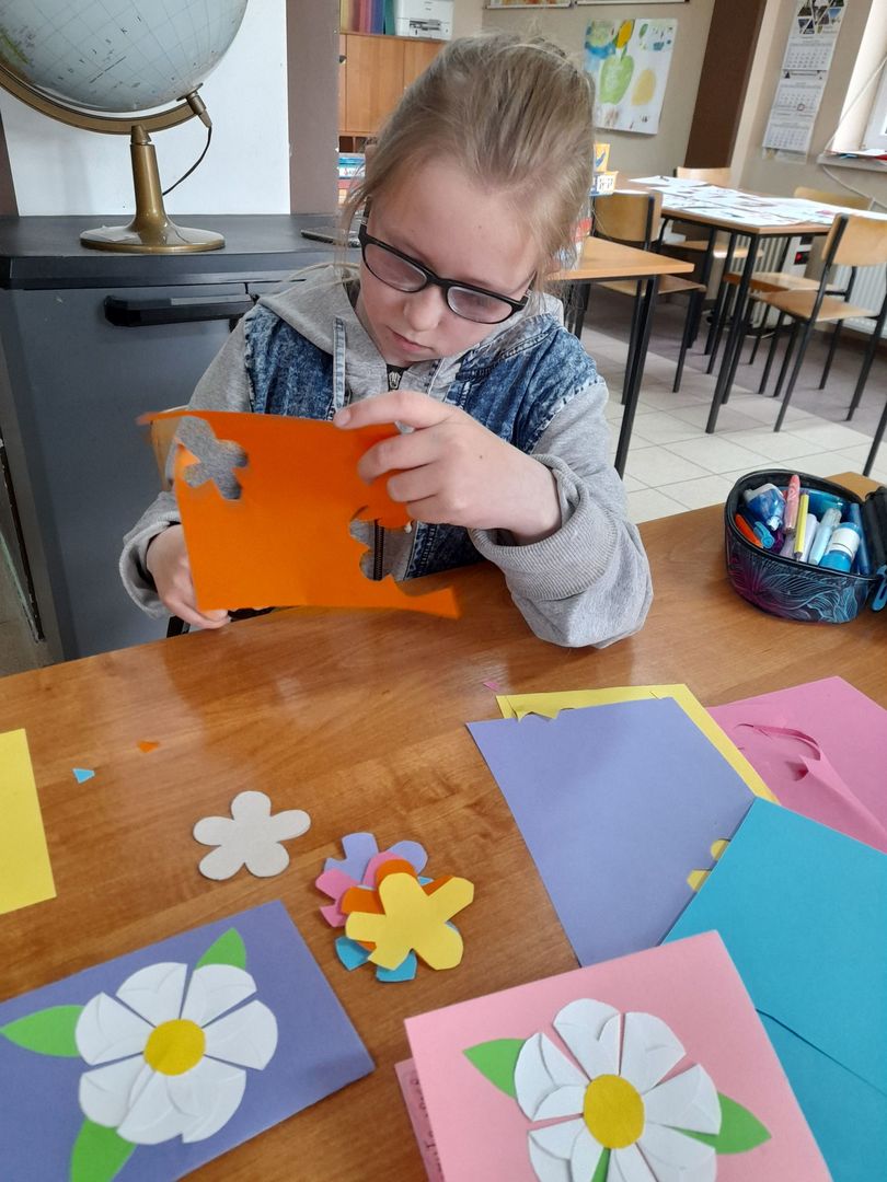 Chłopiec z Placówki Wsparcia Dziennego w Sulechowie wycina kwiatki z kolorowego papieru.