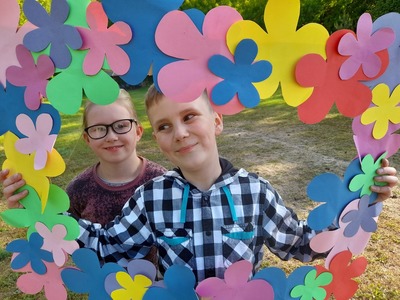 Dwoje dzieci z Placówki Wsparcia Dziennego w Sulechowie w fotoramce z kwiatków.