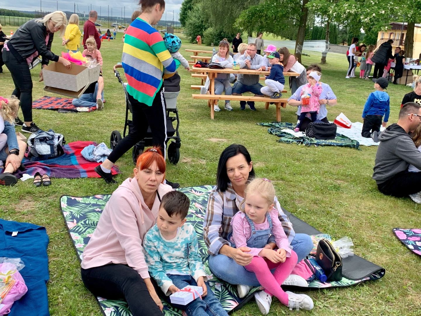 Mamy z dziećmi na kocykach podczas pikniku rodzinnego.