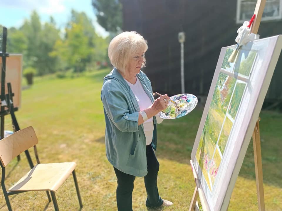Malarka przed sztalugą podczas wykańczania obrazu.