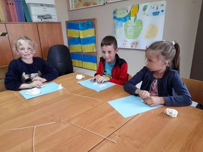 Dwie dziewczynki i chłopiec lepiący figurki z masy solnej.