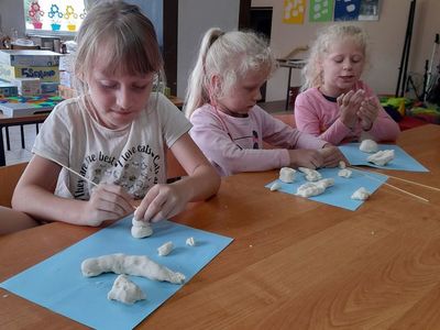 Trzy dziewczynki lepiące figurki z masy solnej.
