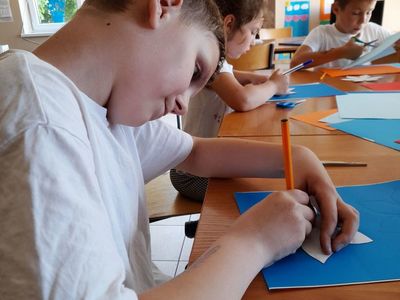 Chłopiec i dwie dziewczynki z Placówki Wsparcia Dziennego w Sulechowie rysujący kwiaty.