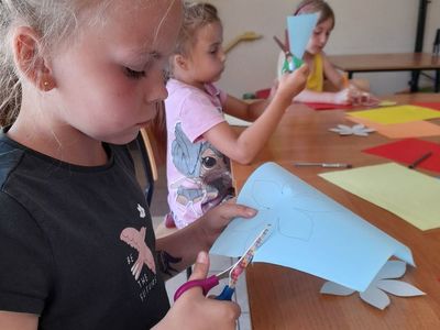 Dwie dziewczynki z Placówki Wsparcia Dziennego w Sulechowie wycinajace kwiaty z kolorowego papieru.