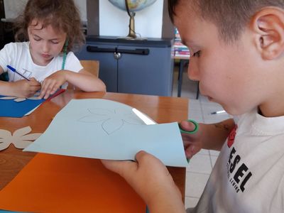 Dziewczynka i chłopiec z Placówki Wsparcia Dziennego w Sulechowie wycinający kwiaty z kolorowego papieru.