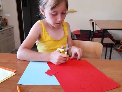Dziewczynka z Placówki Wsparcia Dziennego w Sulechowie odrysowująca kwiat z szablonu.