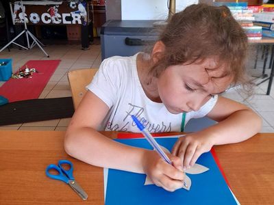 Dziewczynka z PWD w Sulechowie rysująca kwiat na kolorowym papierze.