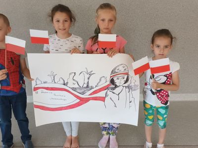 Dzieci z Placówki Wsparcia Dziennego w Ostrowcu prezentują wykonany plakat i flagi biało - czerwone.