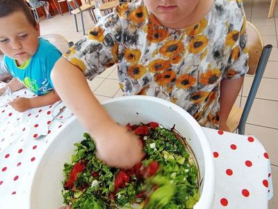 Wychowanka z Placówki Wsparcia Dziennego w Laskach miesza sałatkę warzywną z arbuzem i sosem. 