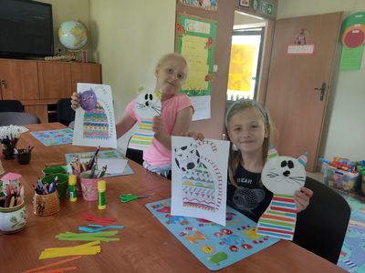 Zdjęcie przedstawia wychowanków PWD Kosierzewo trzymających prace plastyczne z kotem.