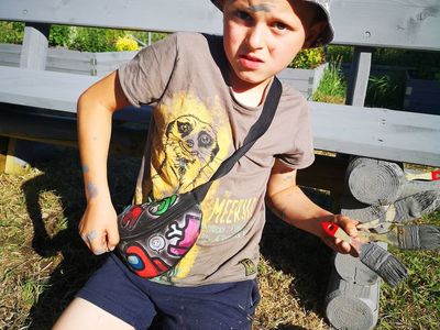 Chłopczyk z Placówki Wsparcia Dziennego w Kusicach podczas malowania ławek. 