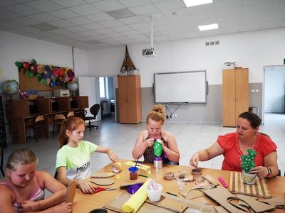 Wychowawczyni Placówki Wsparcia Dziennego w Kusicach wraz z trzema dziewczynkami wykonuje kartonowe kaktusy.