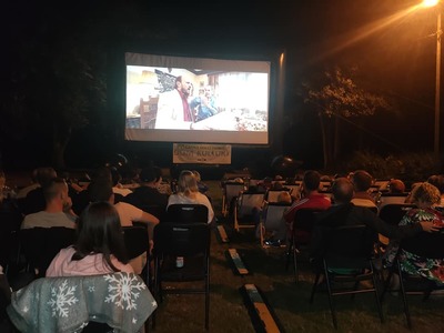 Widzowie Letniego Kina na leżakach w parku w Niemicy i dmuchany ekran, na którym wyświetlany jest film "Zupa nic". 