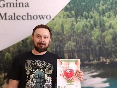Dawca pozuje z dyplomem na tle ścianki Gminy Malechowo.