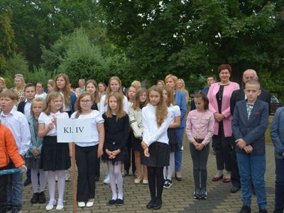 Uczniowie klasy czwartej w wychowawcą w czasie apelu szkolnego.