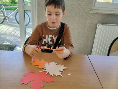 Chłopiec z Kusic wykonuje papierowe liście.