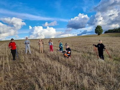 Dzieci z Placówki Wsparcia Dziennego w Sulechowie podczas spaceru z kijkami do nordic walking. Dzieci pozują do zdjęcia stojąc na ściernisku.