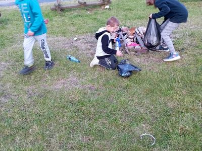 Wychowankowie z Placówki Wsparcia Dziennego w Laskach sprzątają teren przy świetlicy.
