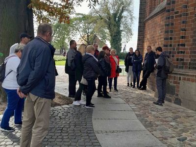Grupa podróżników z Sulechówka wsłuchana w opowieść przewodnika.
