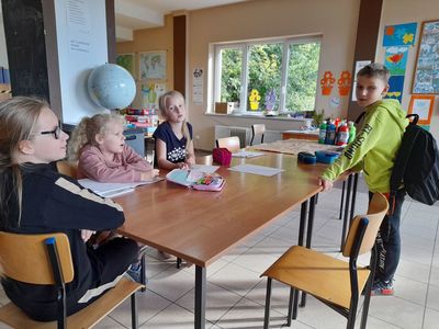 Trzy dziewczynki i chłopiec z Placówki Wsparcia Dziennego w Sulechowie podczas odrabiania lekcji.