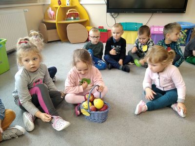 Dzieci z Przedszkola w Ostrowcu opisują jabłka zgromadzone w koszyczku.